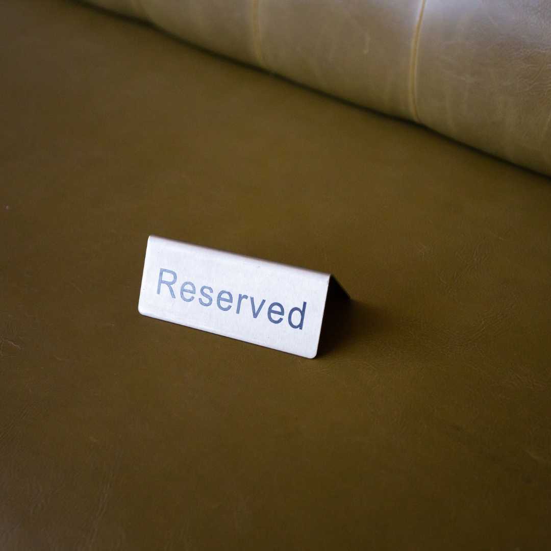 A white “Reserved” sign placed on a brown leather seat, symbolizing limited seats available for Chak.ai Academy workshops. ecommerce consultant hong kong services