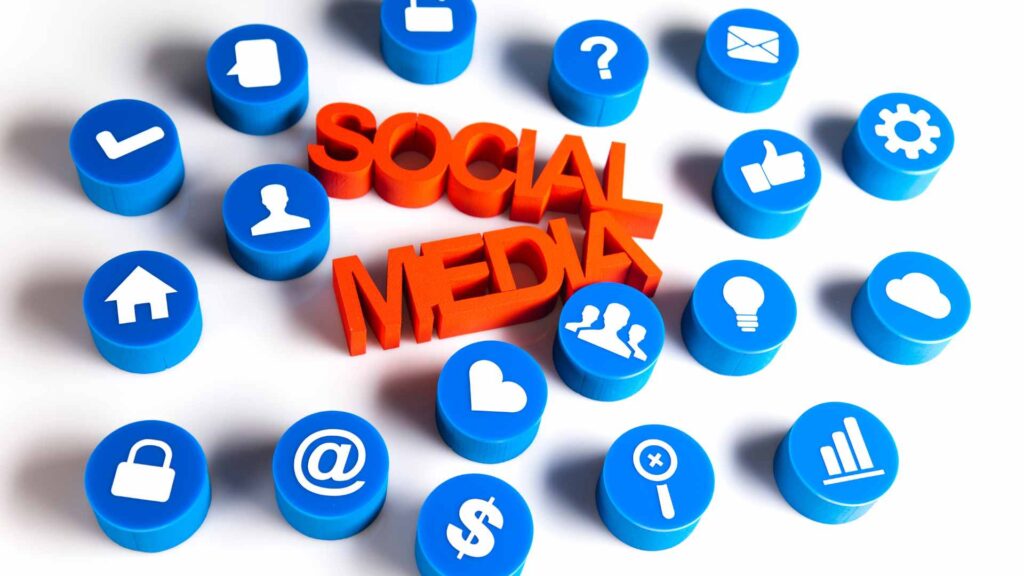 The words SOCIAL MEDIA in orange, surrounded by blue icons representing different functions like likes, comments, user profiles, and analytics.